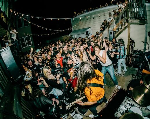 The All-American Rejects playing a house party — crowd with phones up, hands in the air
